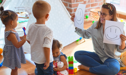 Woman holding up 2 pieces of paper to two children